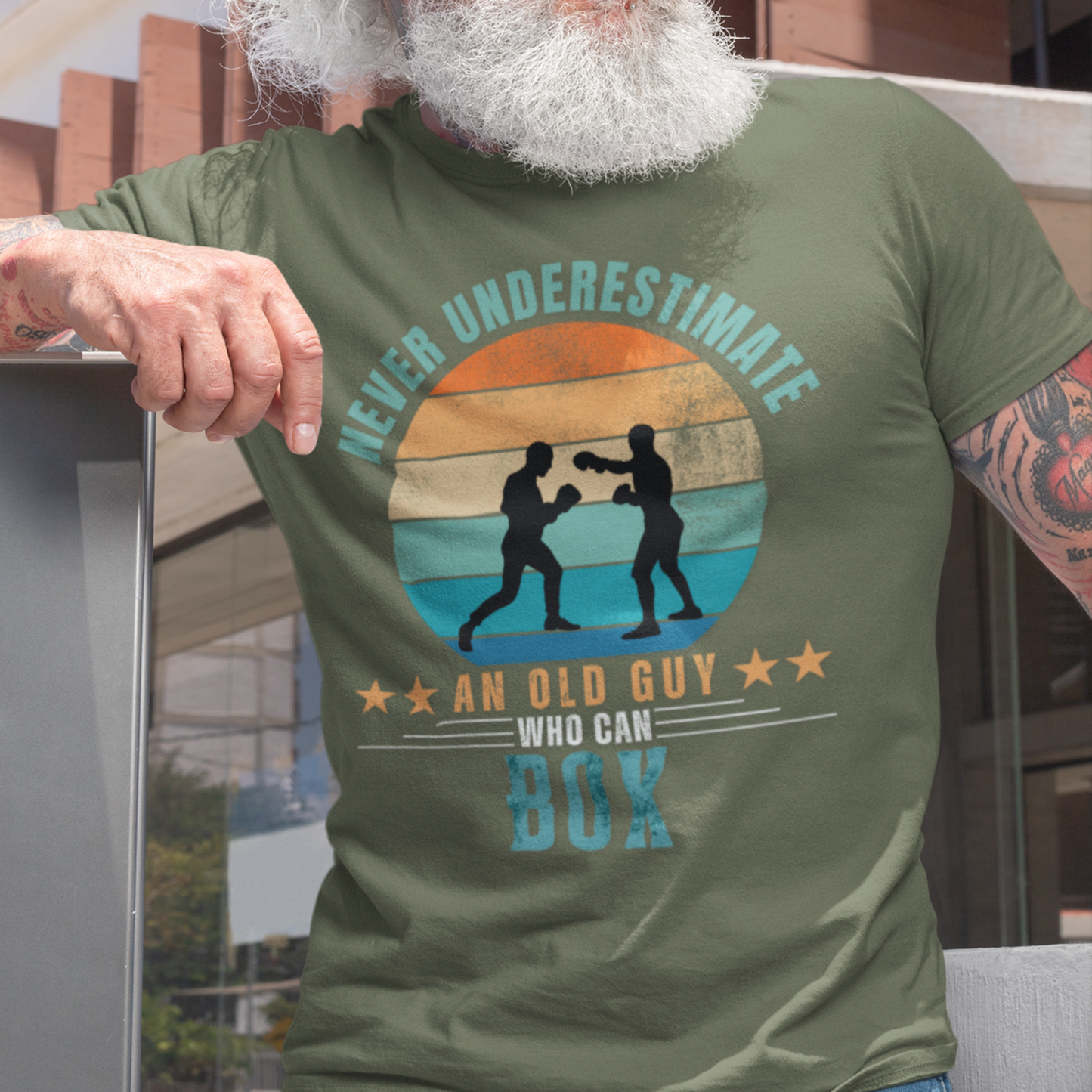 Military green tee featuring silhouette two guys boxing against a distressed striped sunset