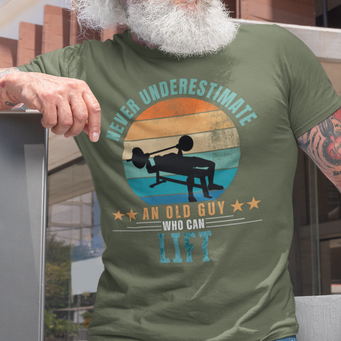 Military green tee featuring silhouette of a guy performing a bench press against a distressed striped sunset