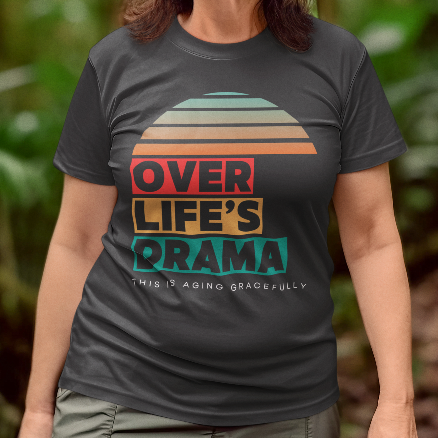 Black t-shirt that reads Over Life's Drama This is Aging Gracefully, featuring colorful block lettering and a rainbow striped sunset.