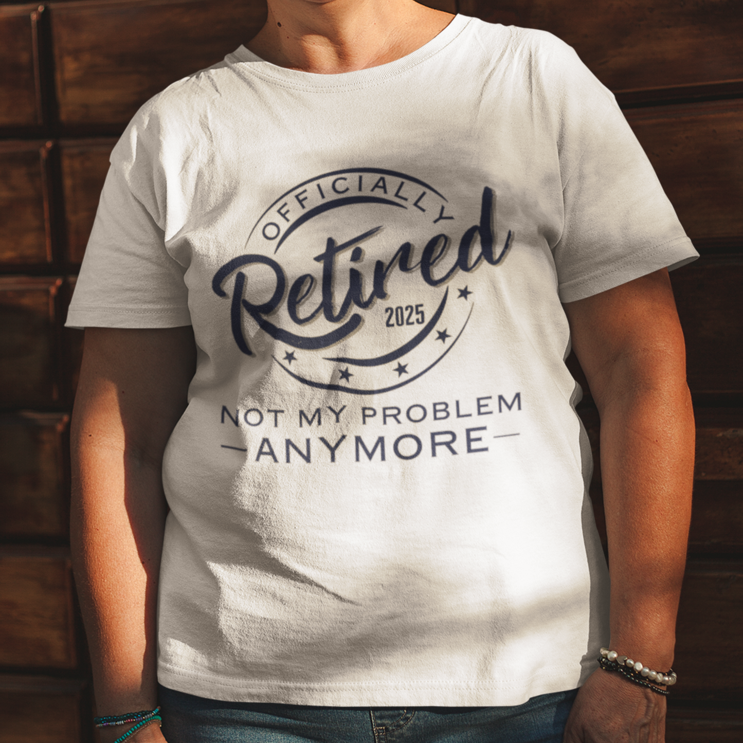 White tee featuring a replica of an official stamp embossing that reads "Officially Retired 2025 Not My Problem Anymore"