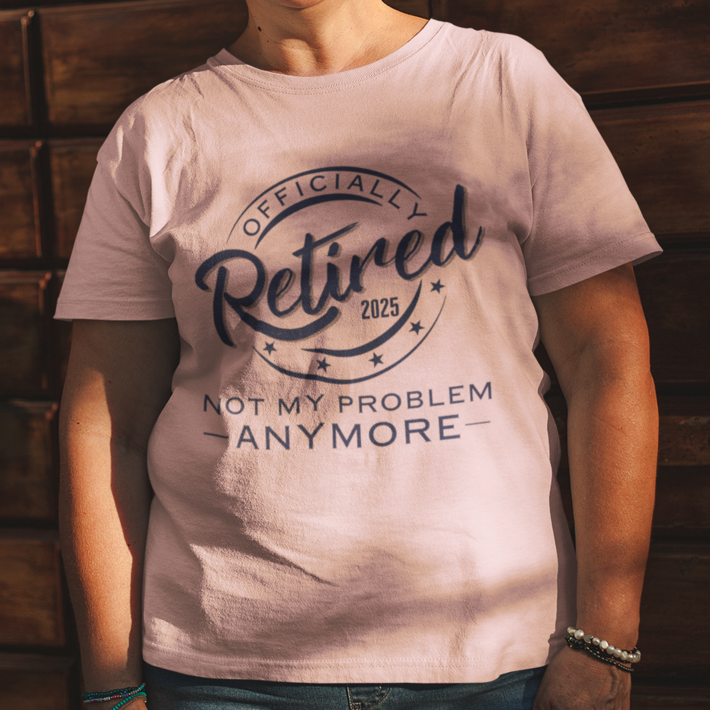 Light pink tee featuring a replica of an official stamp embossing that reads "Officially Retired 2025 Not My Problem Anymore"