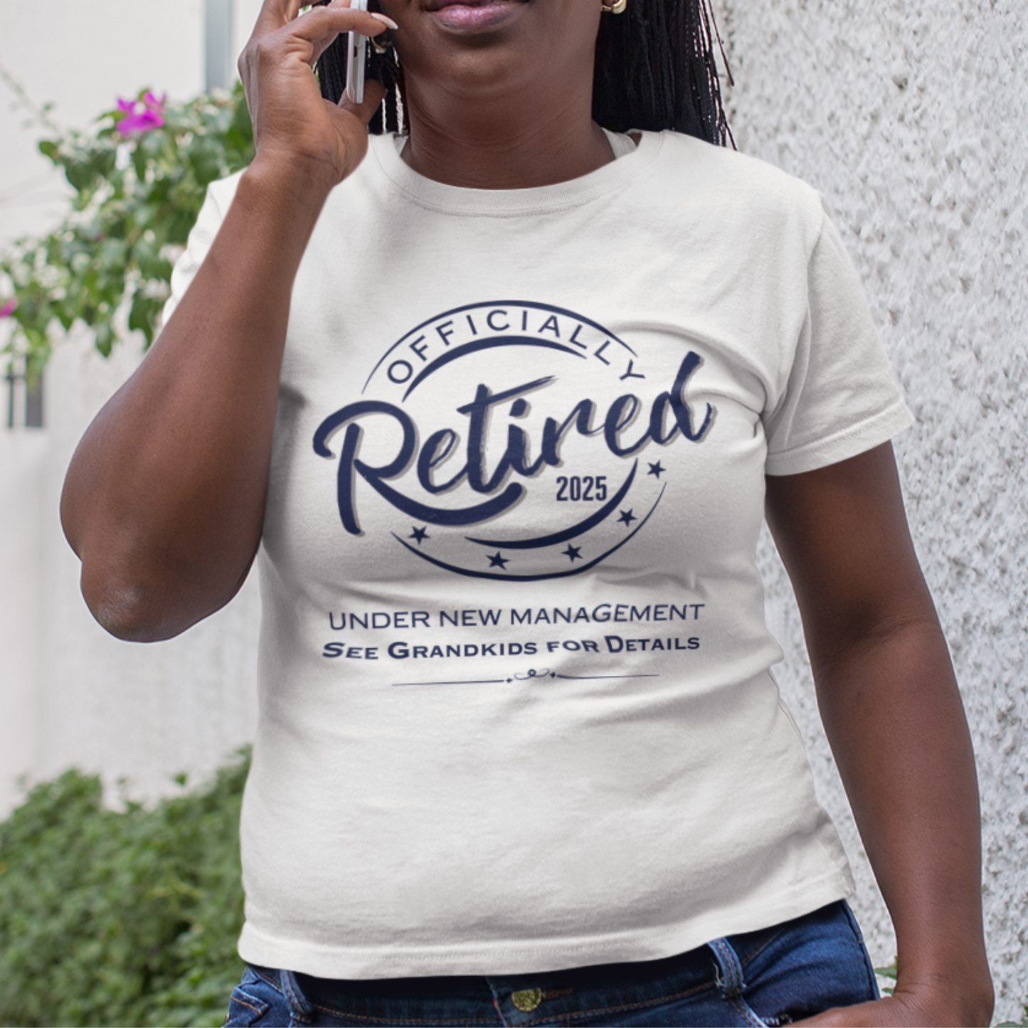White tee featuring a replica of an official stamp embossing that reads "Officially Retired 2025 See Grandkids" on a woman.