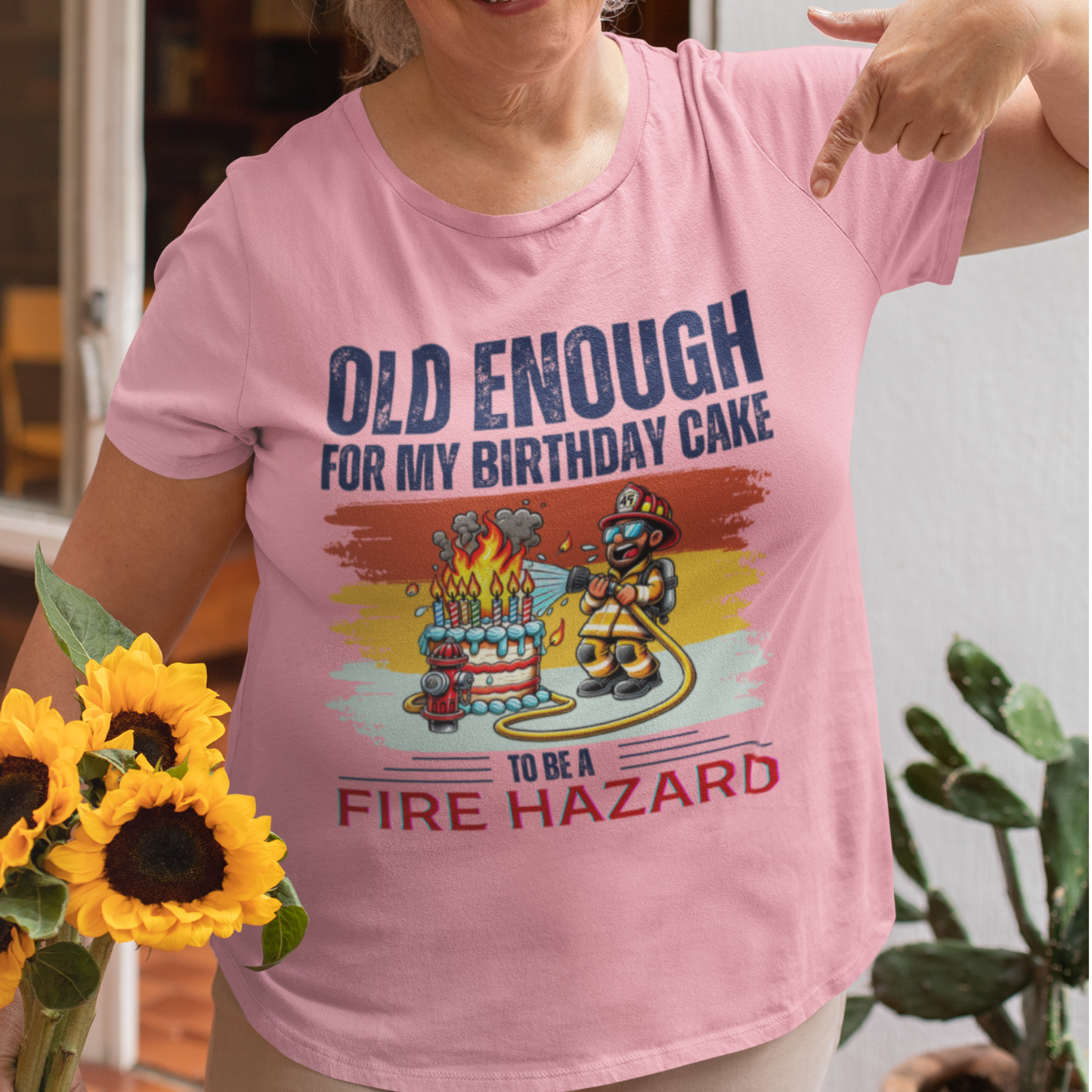 Light pink tee featuring a cartoon fireman putting out the flames from the candles on a birthday cake.