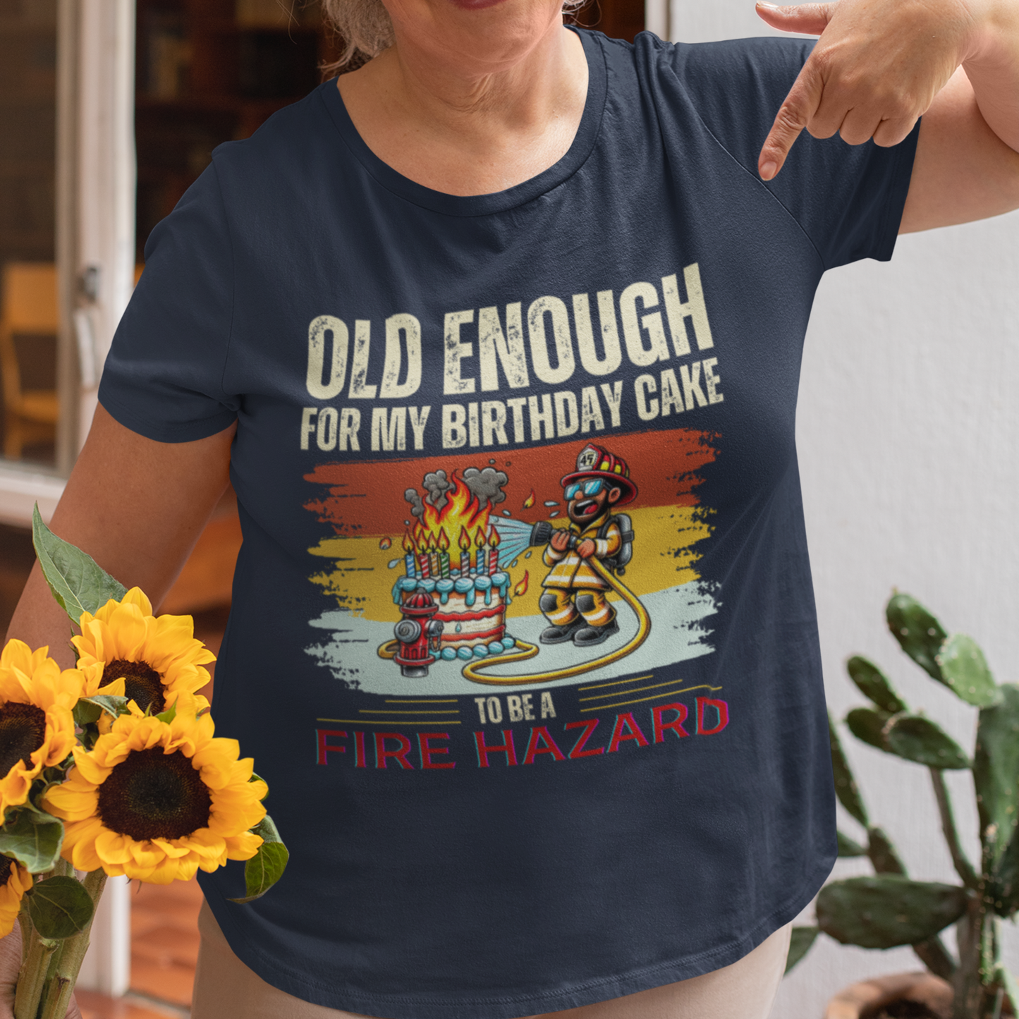 Navy blue tee featuring a cartoon fireman putting out the flames from the candles on a birthday cake.
