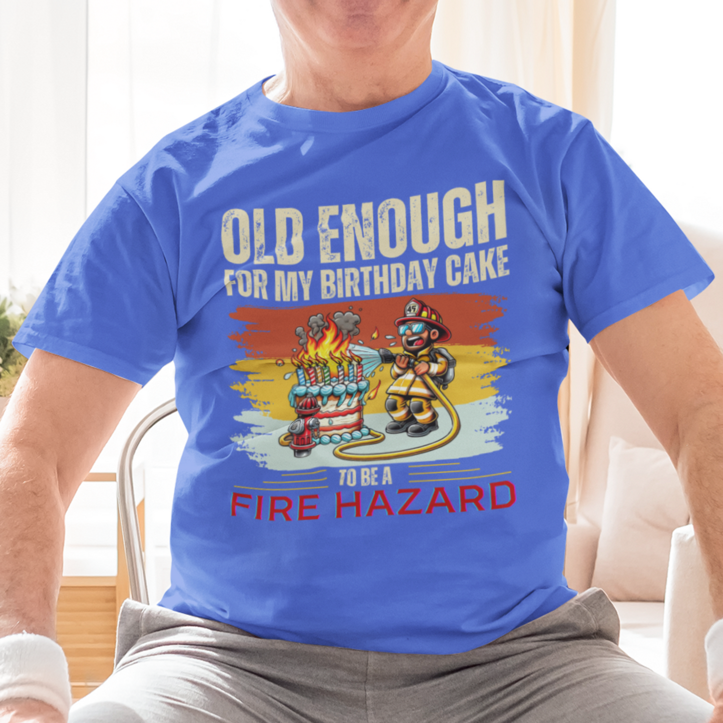 Royal blue tee featuring a cartoon fireman putting out the flames from the candles on a birthday cake.
