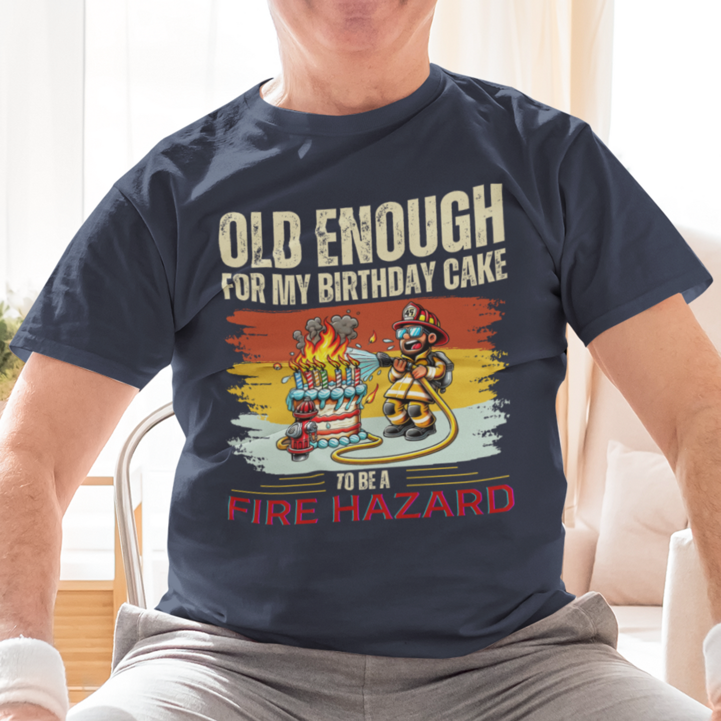 Navy blue tee featuring a cartoon fireman putting out the flames from the candles on a birthday cake.