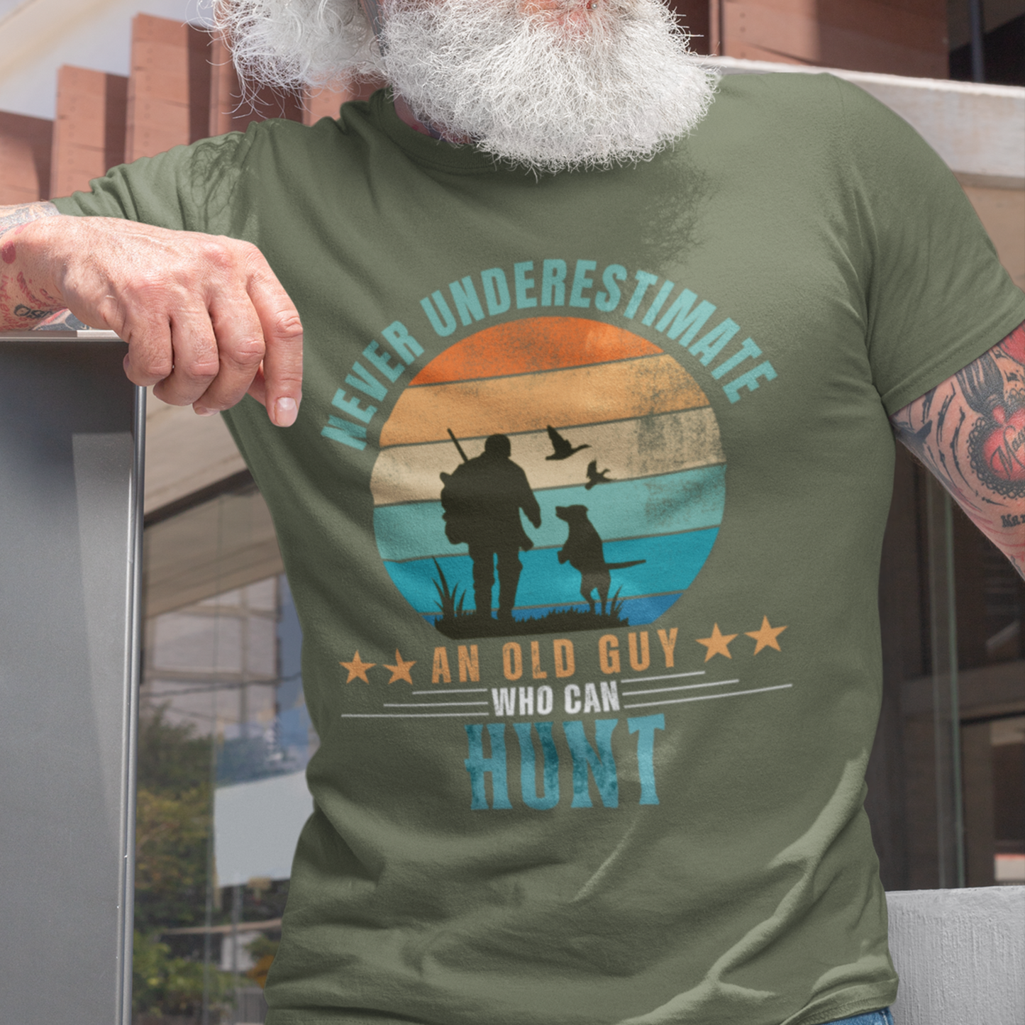 Military green tee featuring silhouette of a hunter with a shotgun and his trusty dog cast against a stylish distressed striped sunset