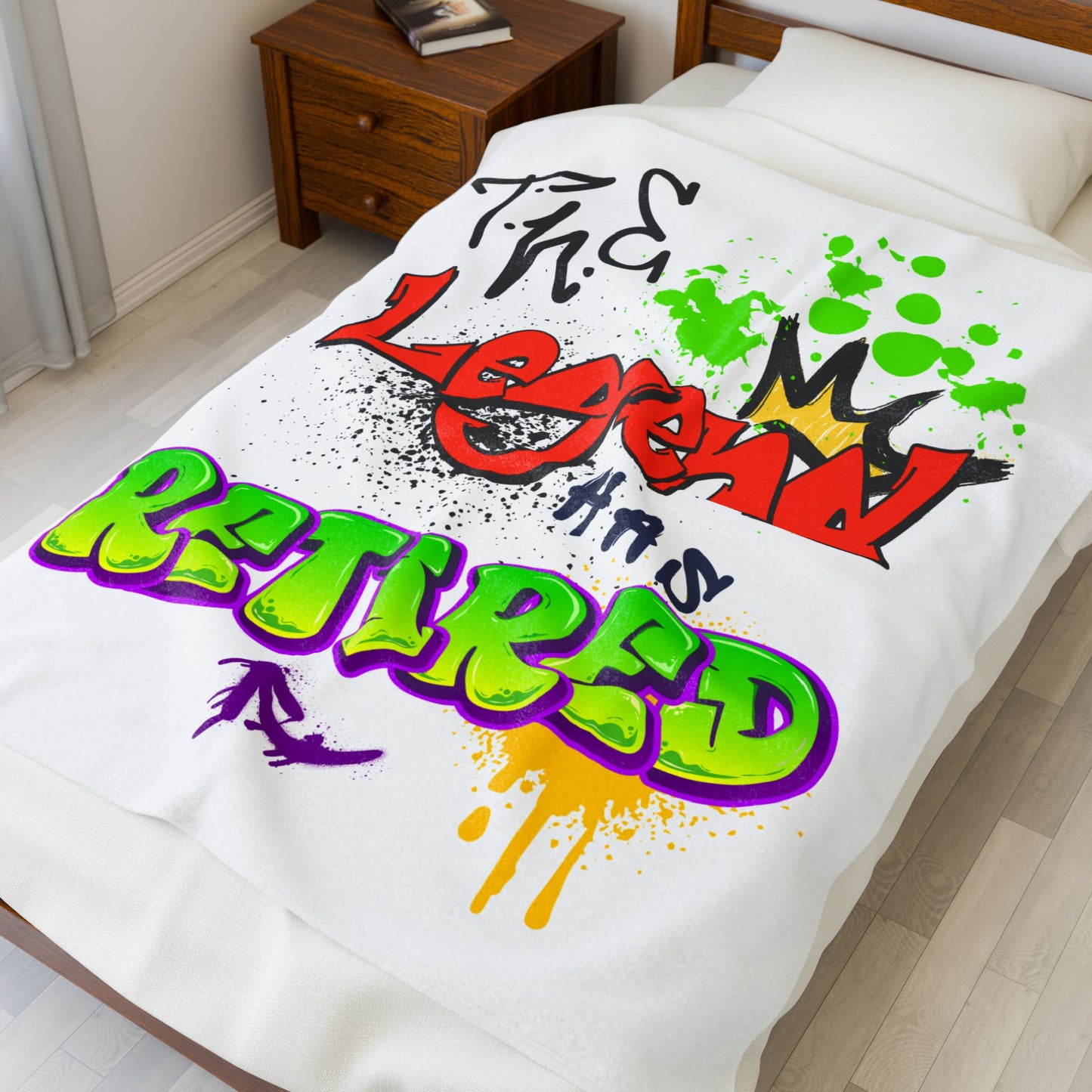 Colorful text design on a 50X60 white blanket in a bedroom setting that reads "The Legend Has Retired"