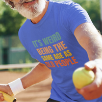 Royal blue tee featuring bold, rainbow-colored lettering reads It’s Weird Being the Same Age as Old People 