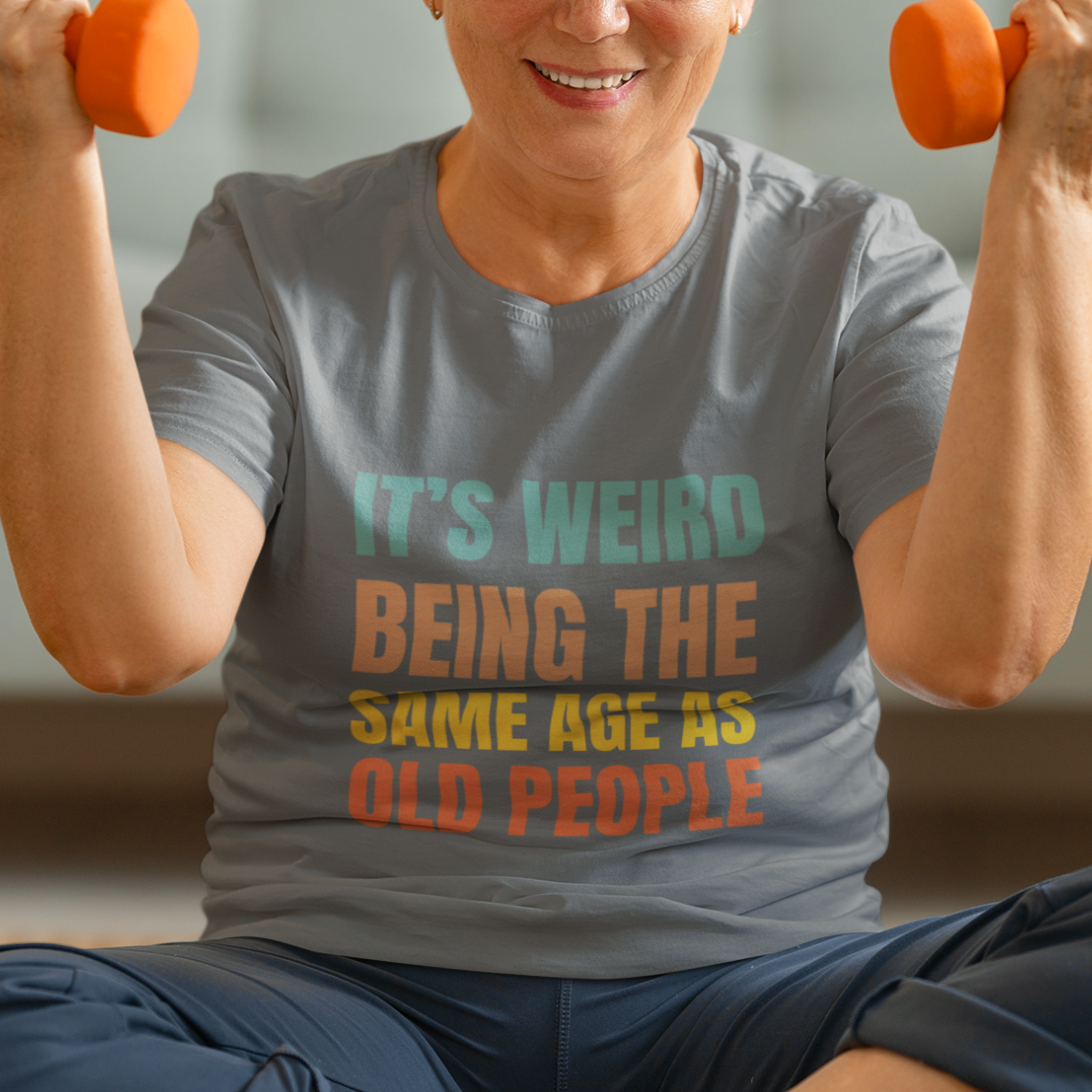 Gray tee featuring bold, rainbow-colored lettering reads It’s Weird Being the Same Age as Old People 