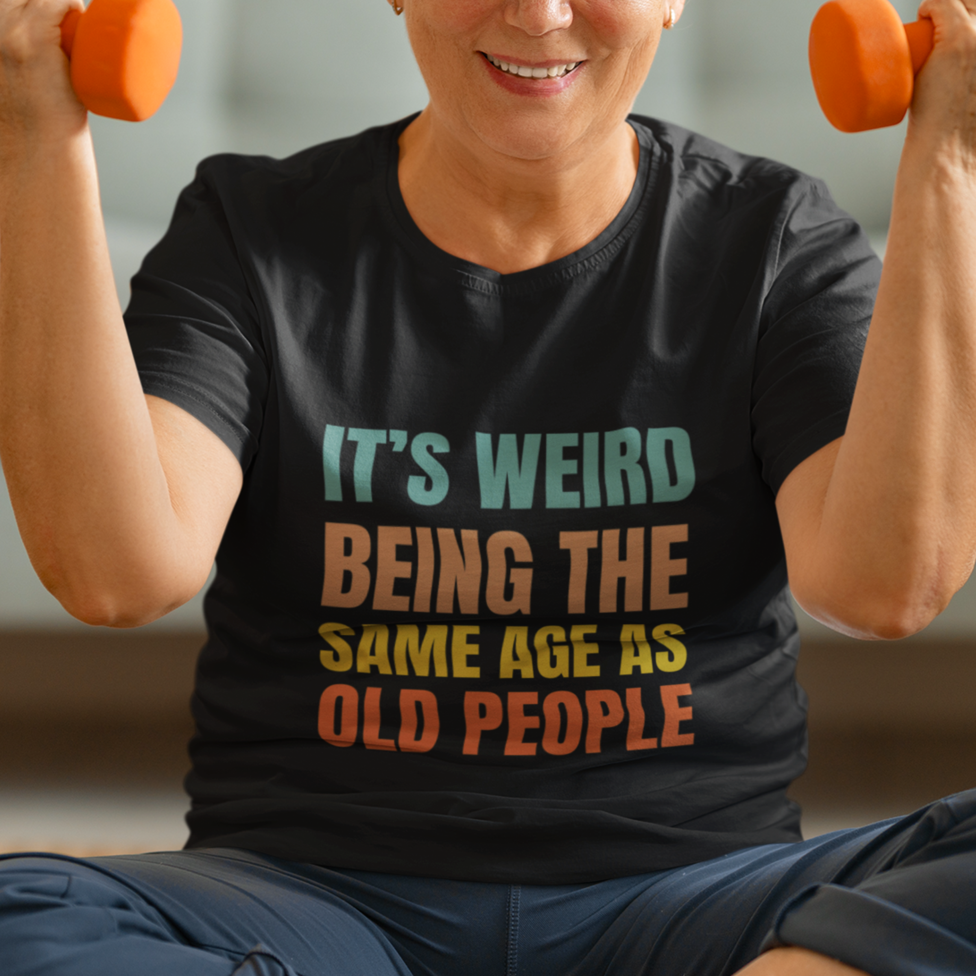 Black tee featuring bold, rainbow-colored lettering reads It’s Weird Being the Same Age as Old People 