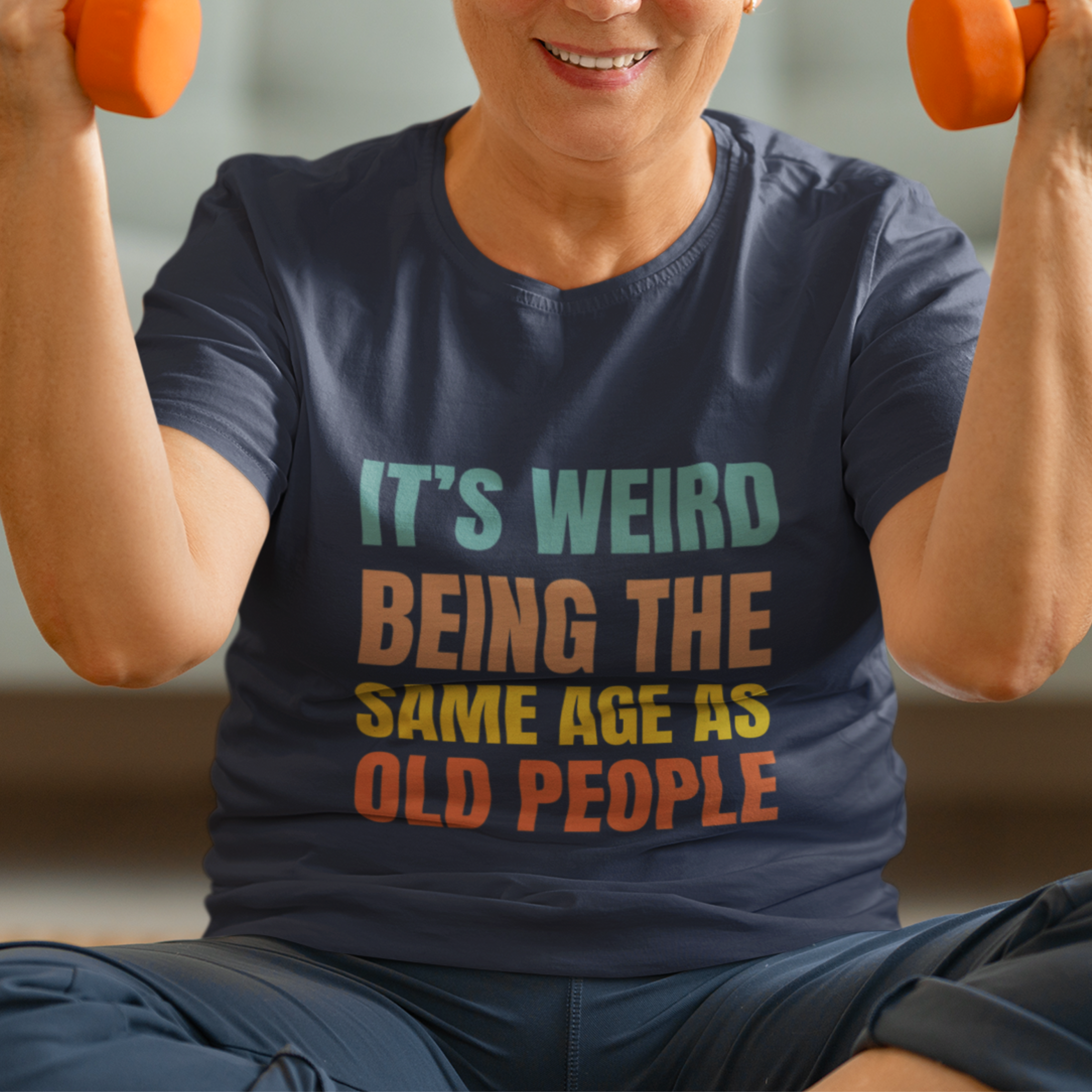 Navy blue tee featuring bold, rainbow-colored lettering reads It’s Weird Being the Same Age as Old People 