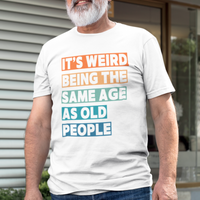 White tee featuring bold, multi-color block lettering reads It’s Weird Being the Same Age as Old People 