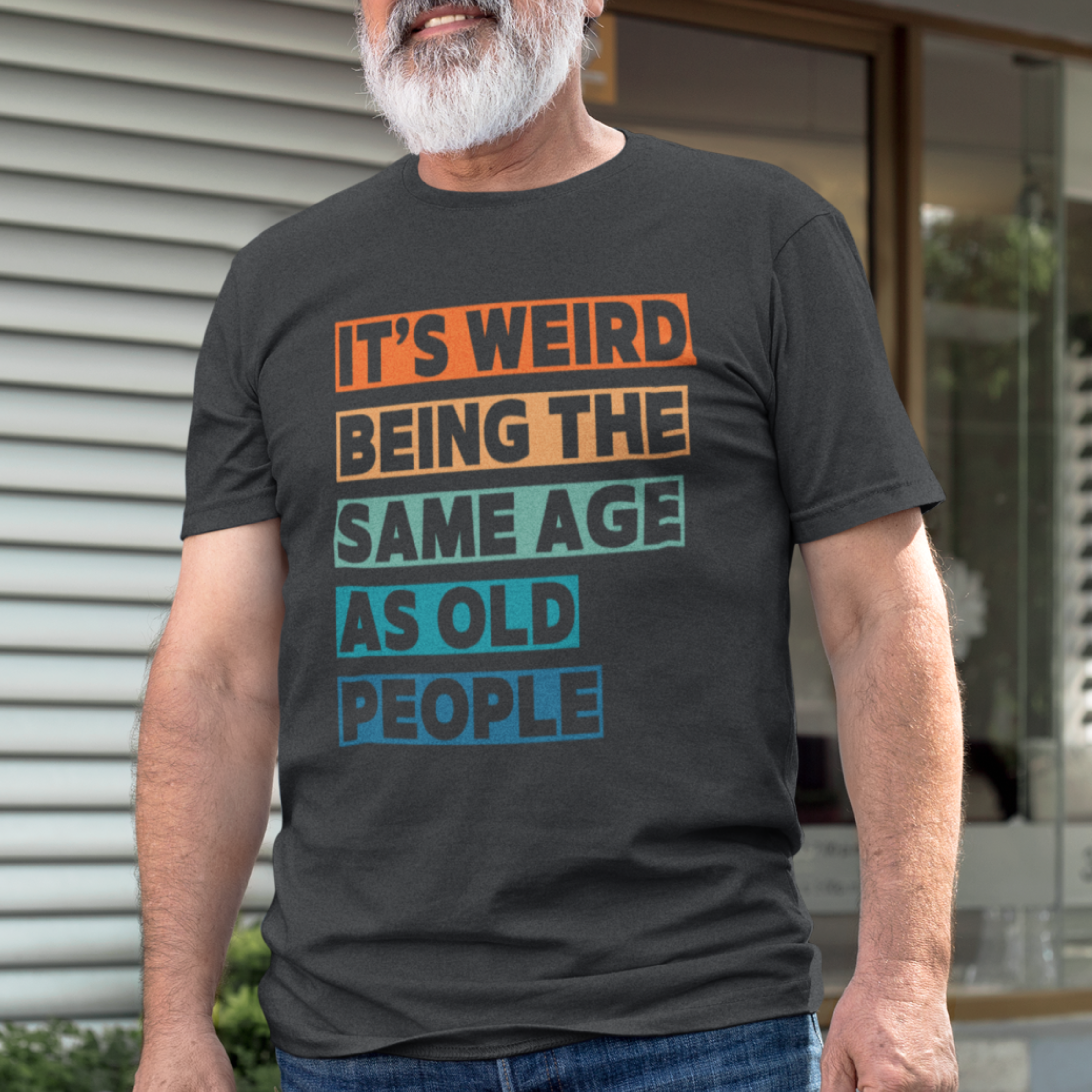 Black tee featuring bold, multi-color block lettering reads It’s Weird Being the Same Age as Old People 