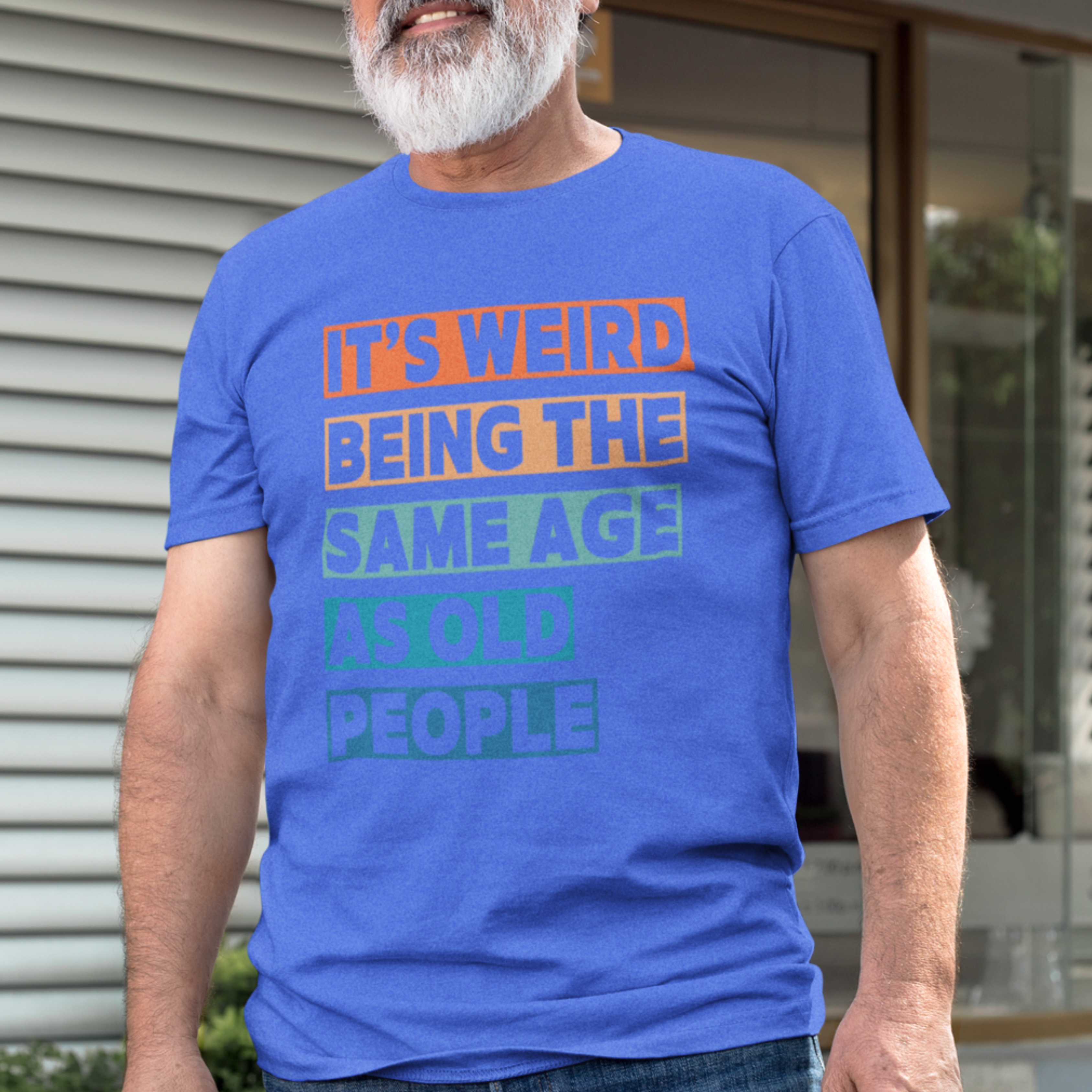 Royal blue tee featuring bold, multi-color block lettering reads It’s Weird Being the Same Age as Old People 