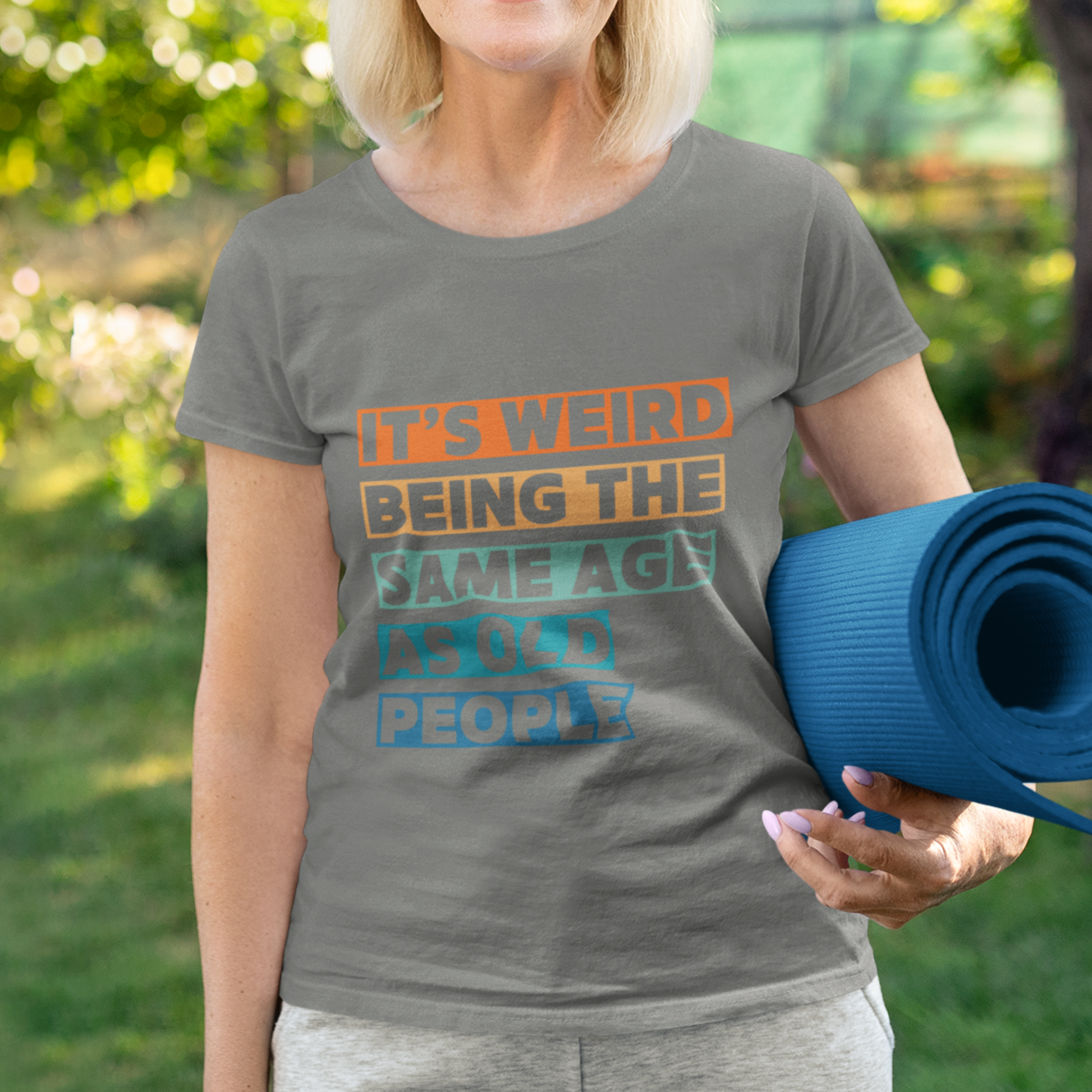 Gray tee featuring bold, multi-color block lettering reads It’s Weird Being the Same Age as Old People 