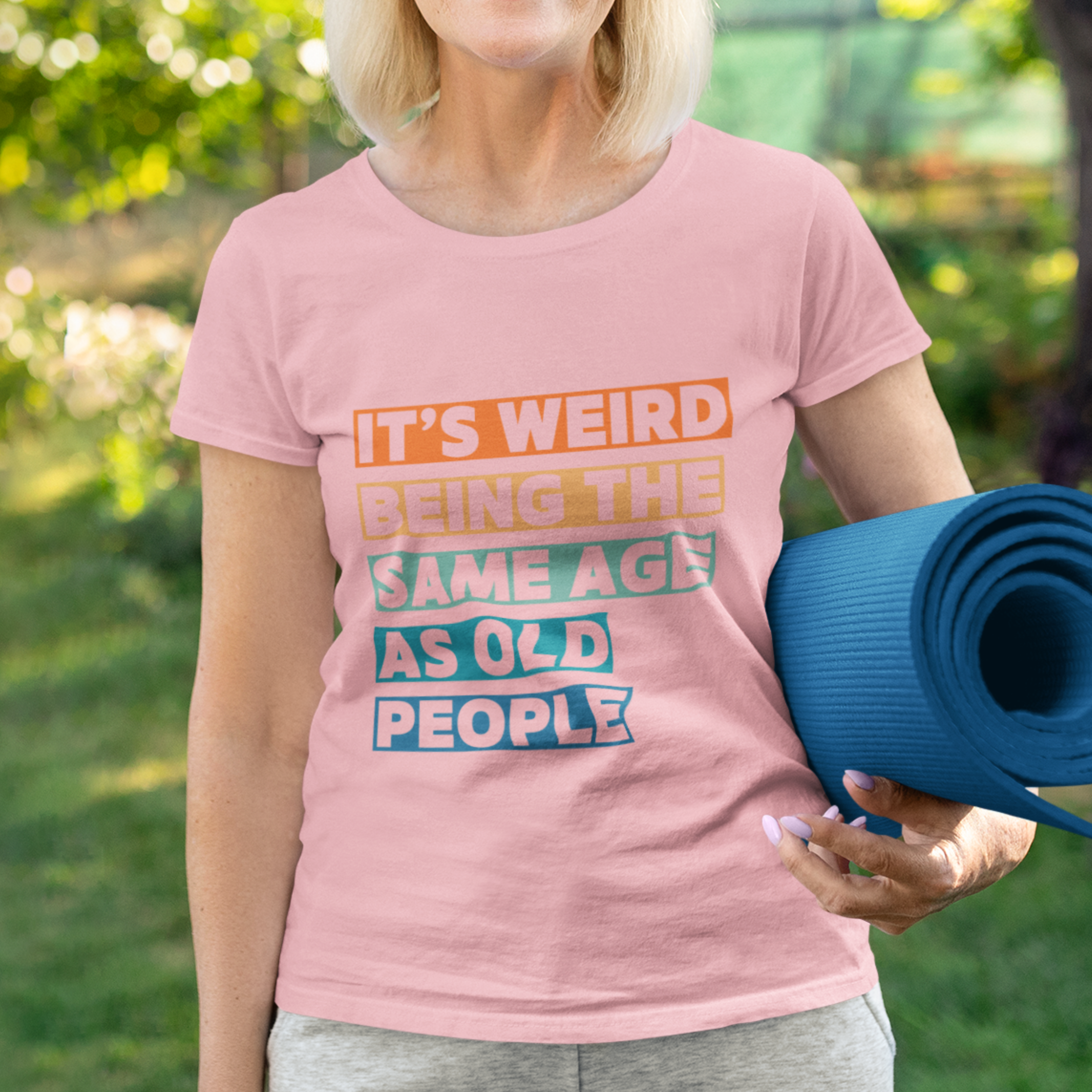 Pink tee featuring bold, multi-color block lettering reads It’s Weird Being the Same Age as Old People 