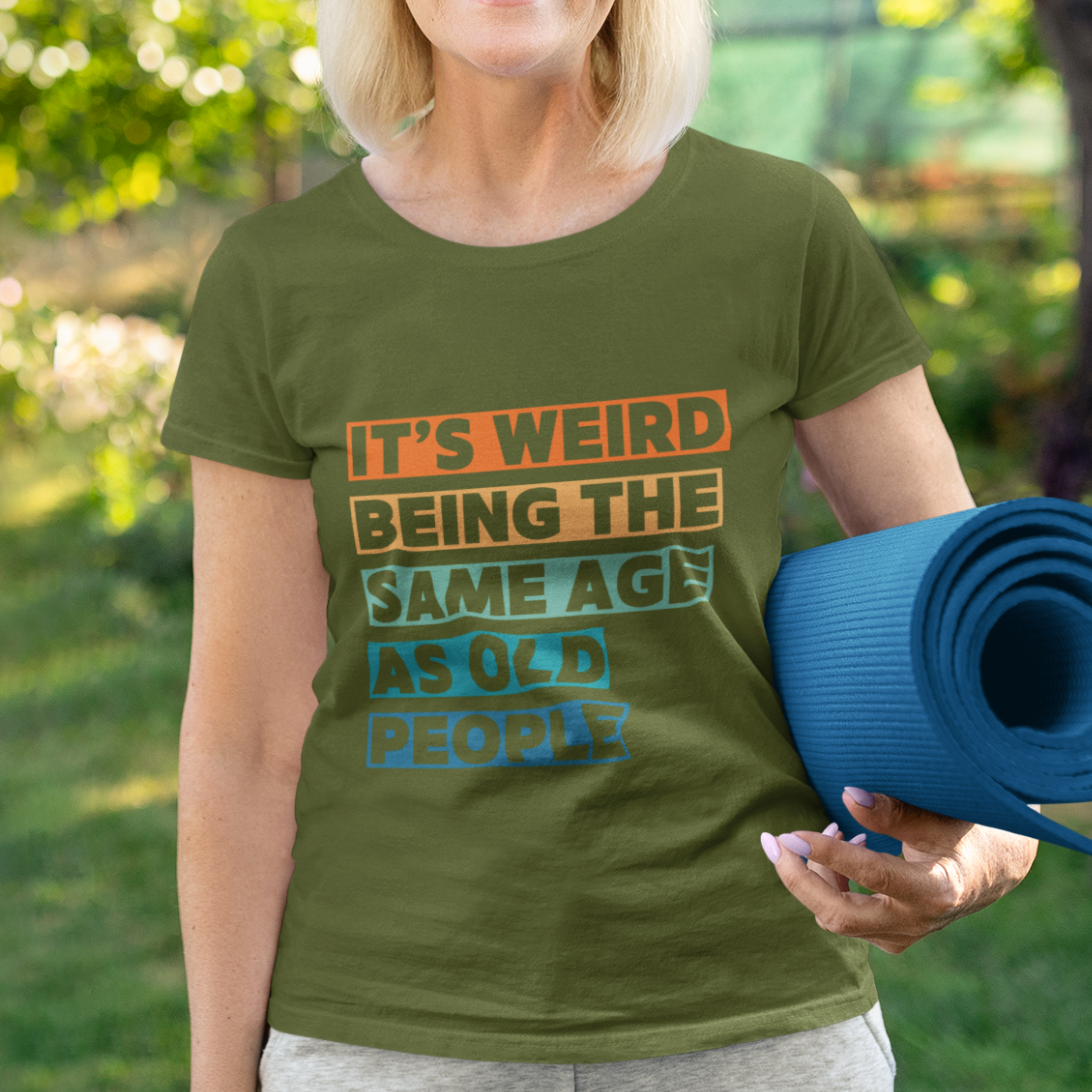 Military green tee featuring bold, multi-color block lettering reads It’s Weird Being the Same Age as Old People 