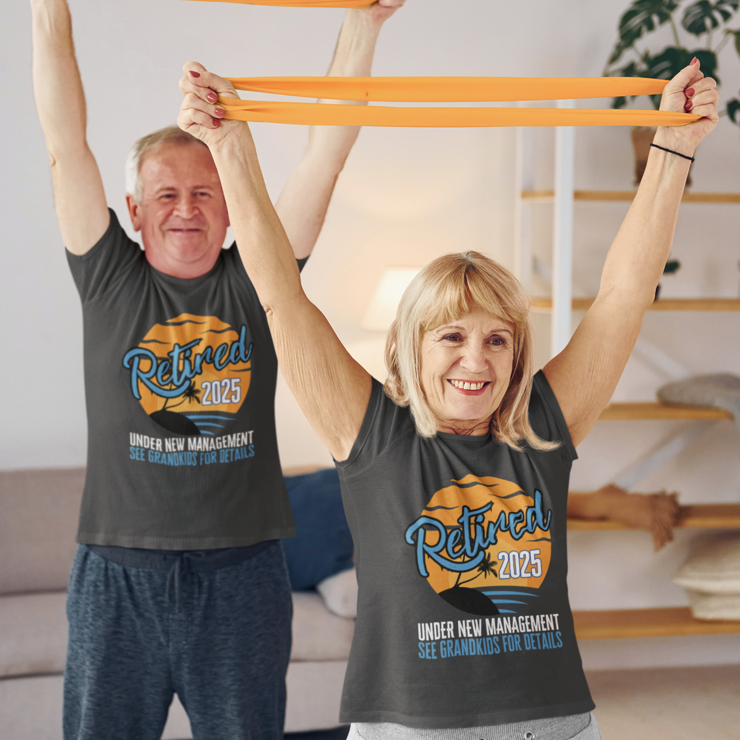 A couple in black t-shirts featuring a sunset beach scene that reads Retired 2025 Under New Management See Grandkids for Details.