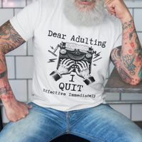 White t-shirt featuring a man's hand typing out his resignation letter to Adulting on an old typewriter