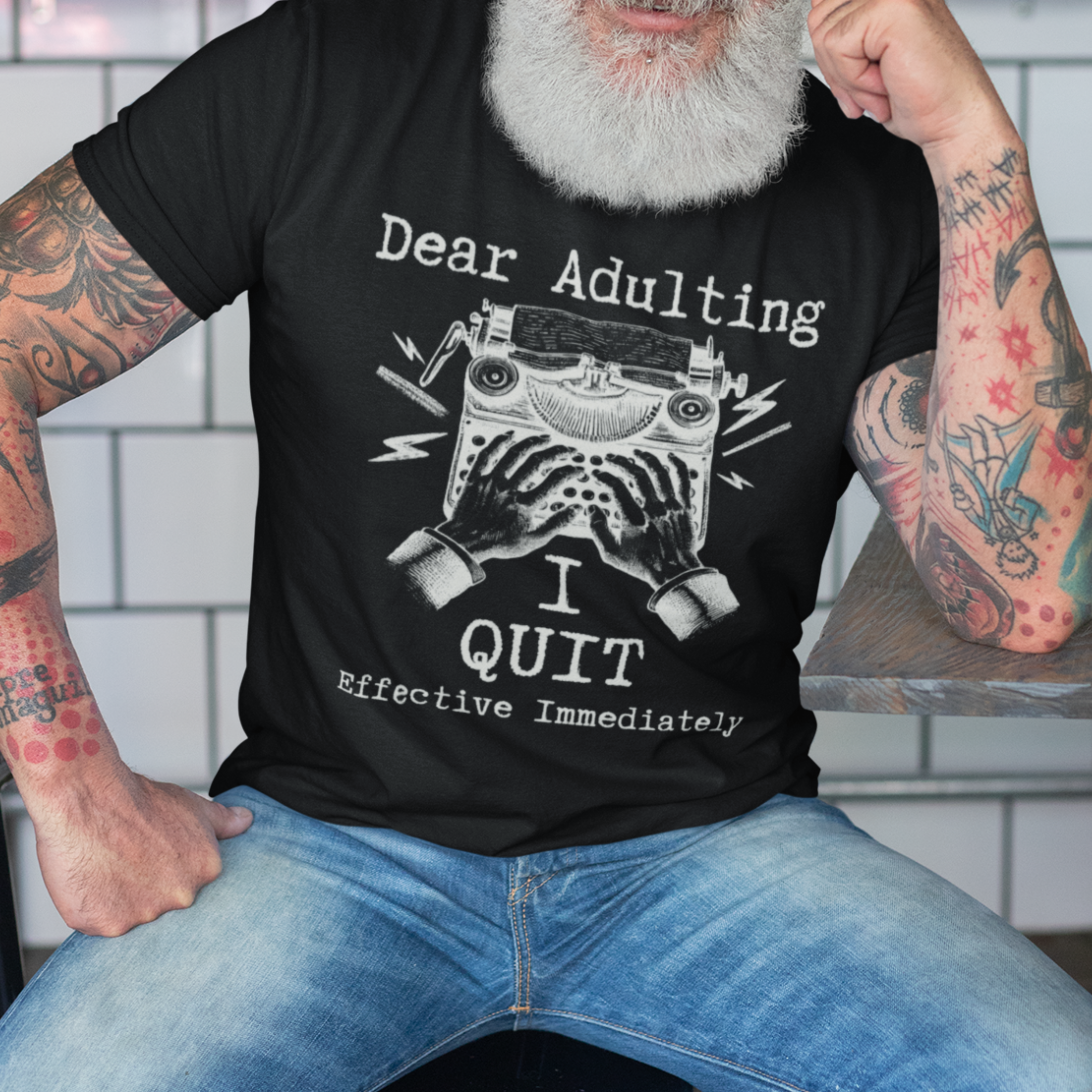 Black t-shirt featuring a man's hand typing out his resignation letter to Adulting on an old typewriter