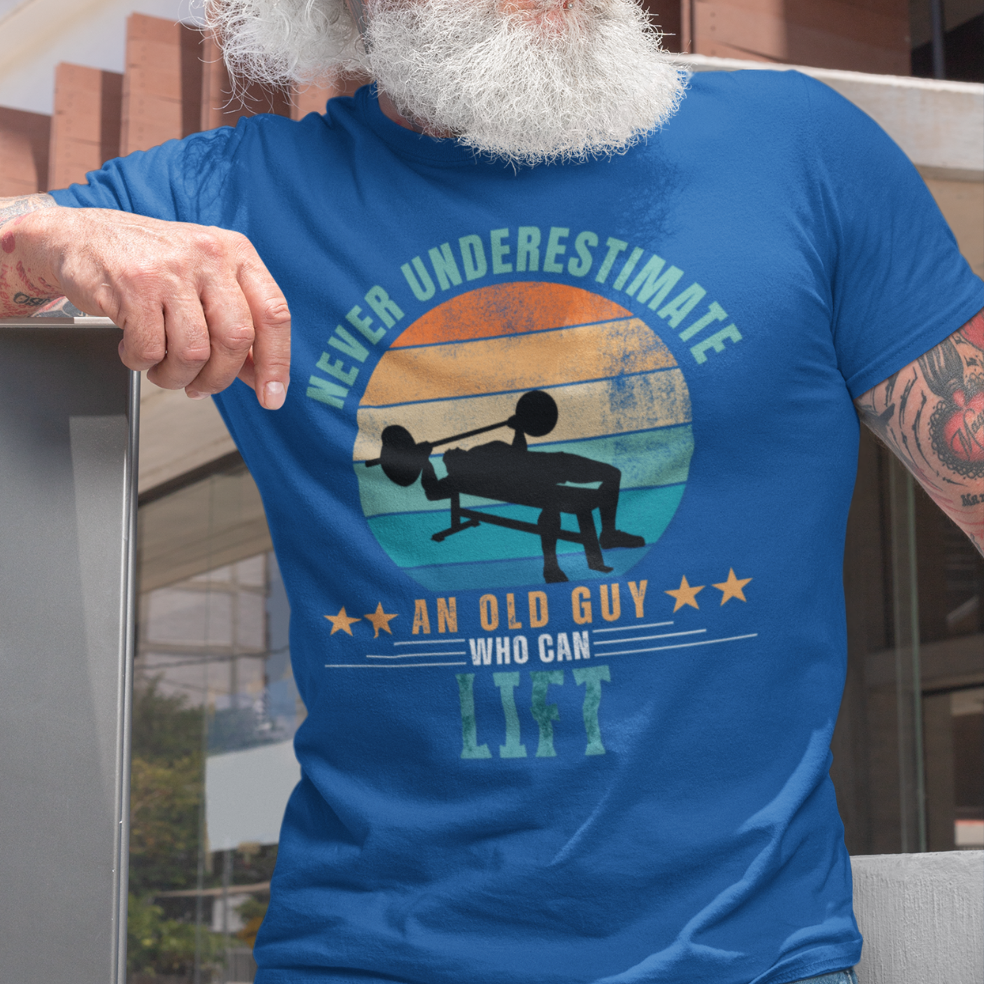 Royal blue tee featuring silhouette of a guy performing a bench press against a distressed striped sunset