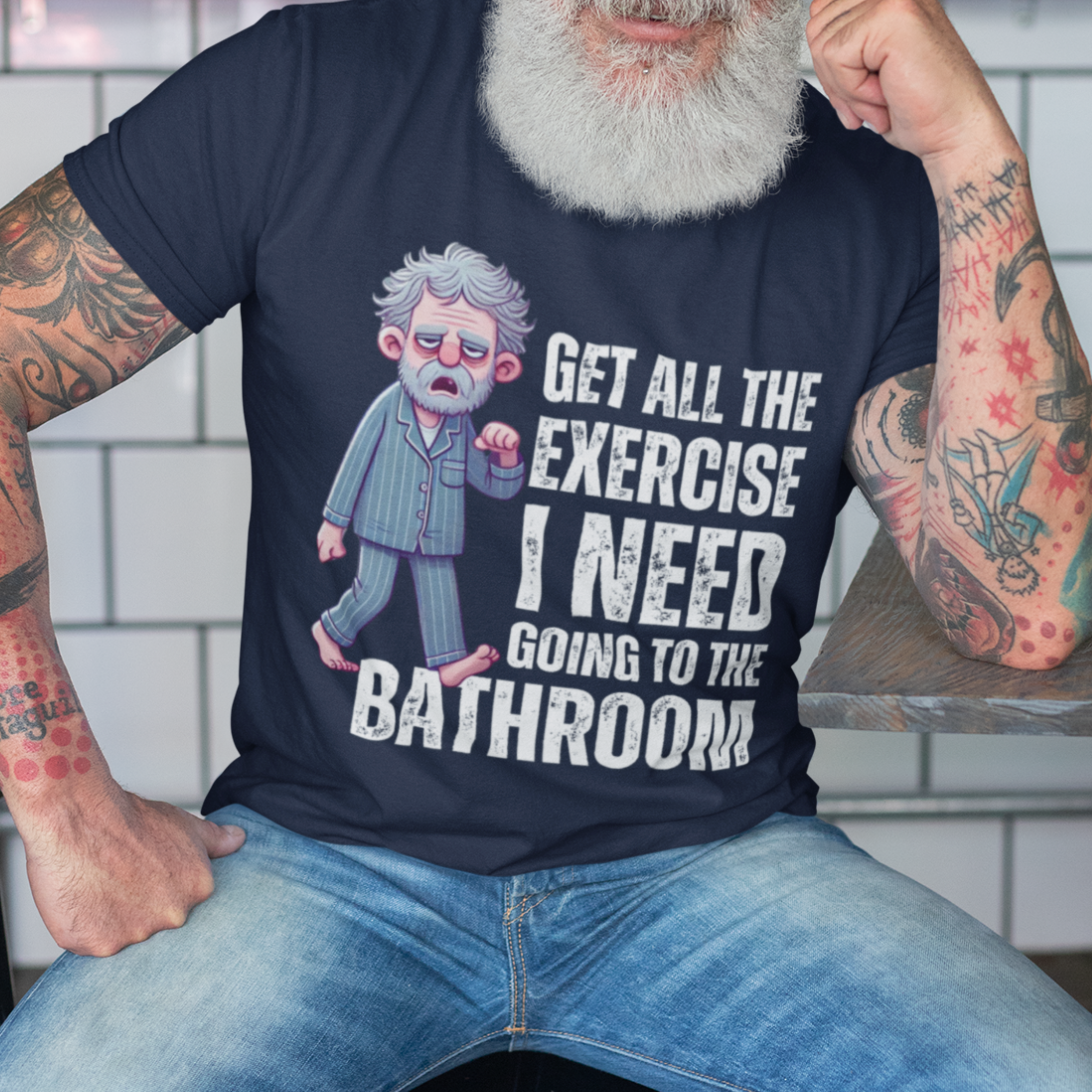 Navy blue t-shirt featuring a gray-haired man in pajamas with distressed bold lettering, "Get All The Exercise I Need Going to the Bathroom"
