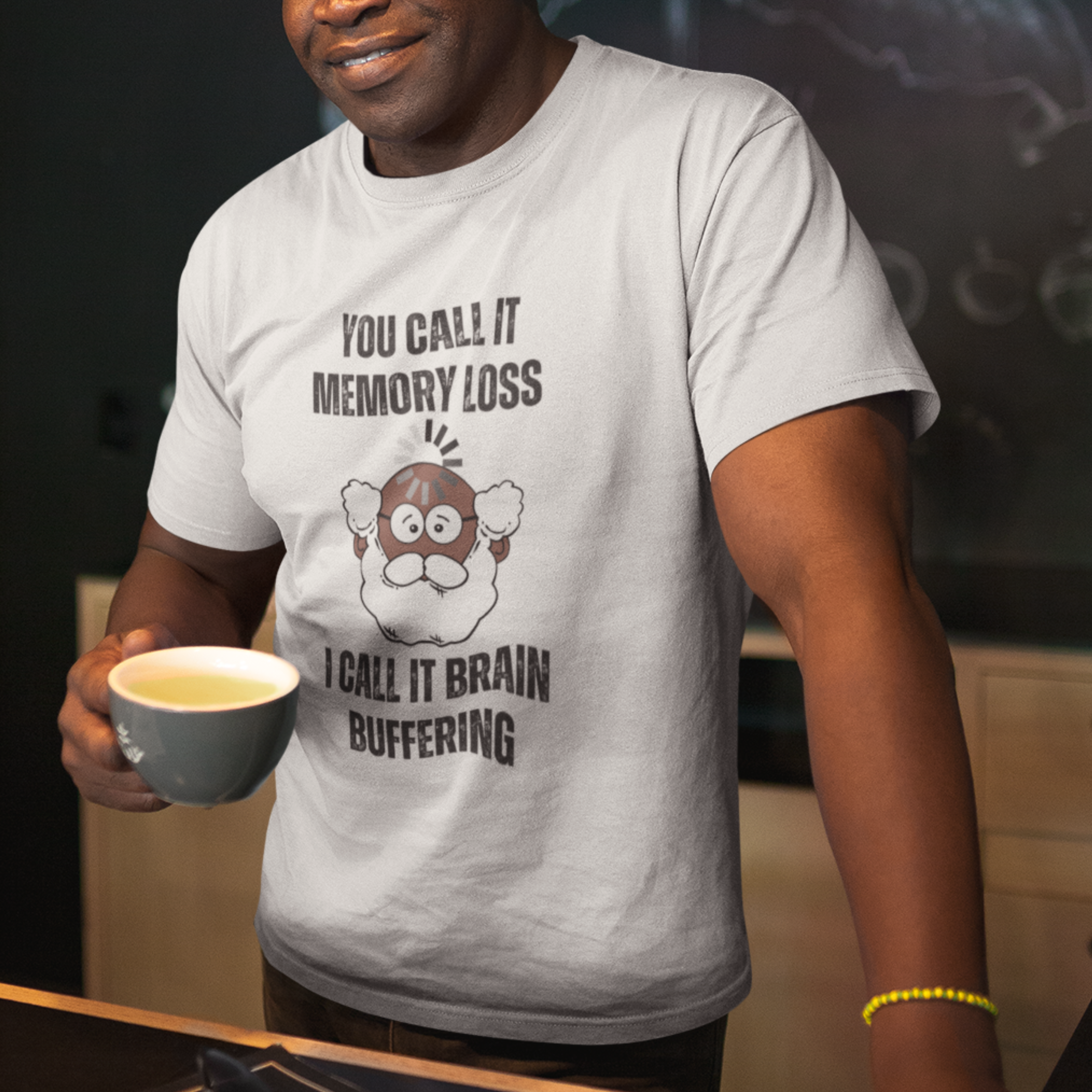 White t-shirt featuring the phrase 'Brain Buffering' with a loading icon graphic and a bald, bearded dark-toned senior.