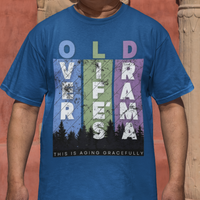 Royal blue t-shirt featuring pastel stripes and lettering with a forest scene in silhouette, stating Over Life's Drama This is Aging Gracefully