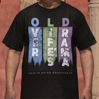Black t-shirt featuring pastel stripes and lettering with a forest scene in silhouette, stating Over Life's Drama This is Aging Gracefully