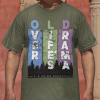 Military green t-shirt featuring pastel stripes and lettering with a forest scene in silhouette, stating Over Life's Drama This is Aging Gracefully