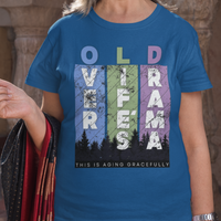 Royal blue t-shirt featuring pastel stripes and lettering with a forest scene in silhouette, stating Over Life's Drama This is Aging Gracefully