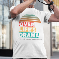 White t-shirt that reads Over Life's Drama This is Aging Gracefully, featuring colorful block lettering and a rainbow striped sunset.