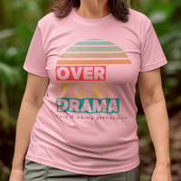 Pink t-shirt that reads Over Life's Drama This is Aging Gracefully, featuring colorful block lettering and a rainbow striped sunset.