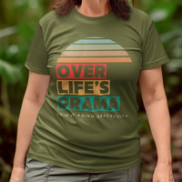 Military green t-shirt that reads Over Life's Drama This is Aging Gracefully, featuring colorful block lettering and a rainbow striped sunset.