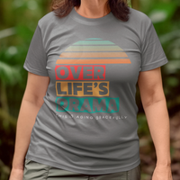 Gray t-shirt that reads Over Life's Drama This is Aging Gracefully, featuring colorful block lettering and a rainbow striped sunset.