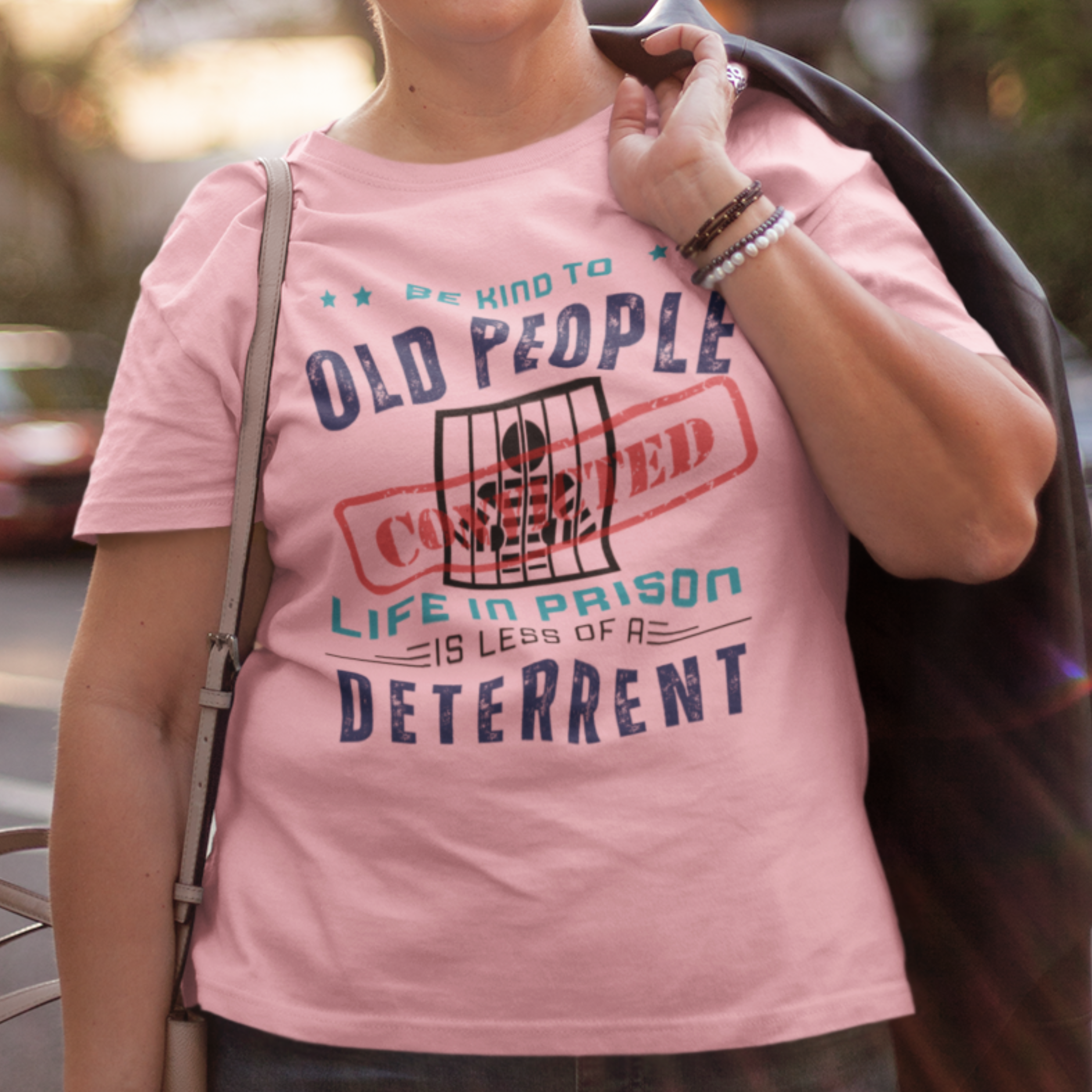 Pink t-shirt that reads Be Kind to Old People Life in Prison is Less of a Deterrent and features a prisoner behind bars pictogram.