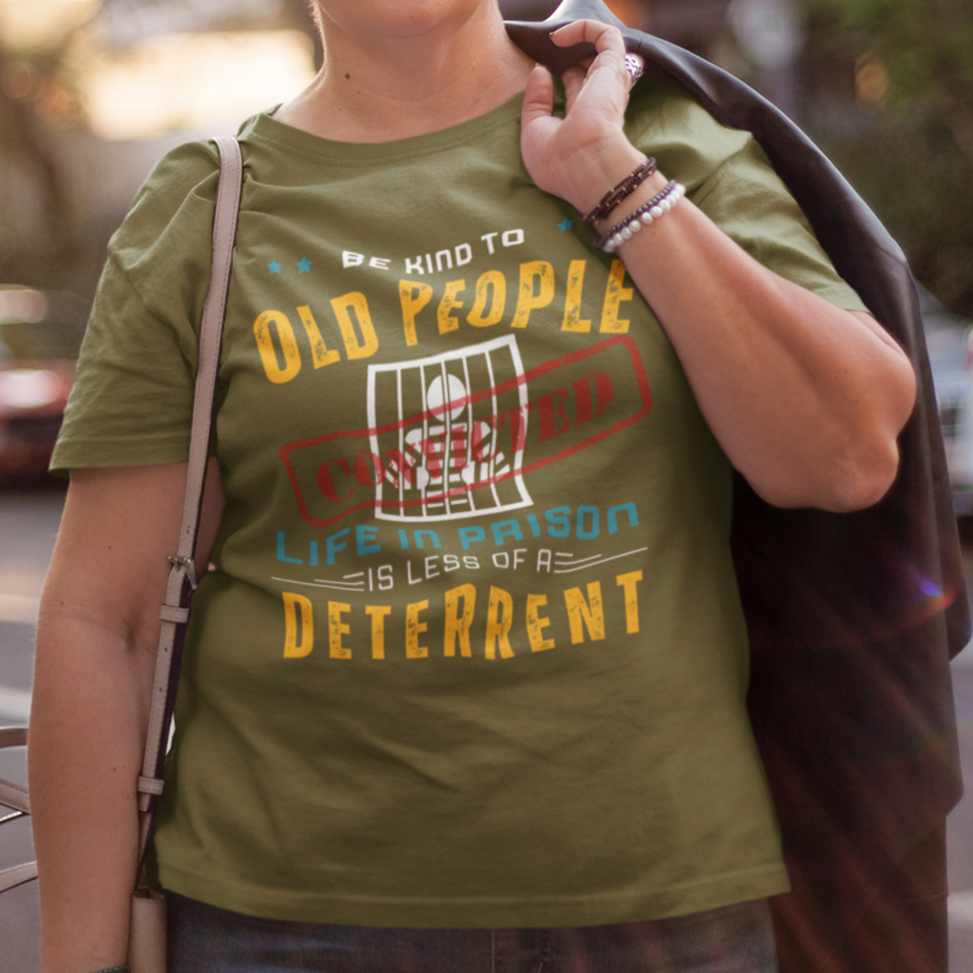 Military green t-shirt that reads Be Kind to Old People Life in Prison is Less of a Deterrent and features a prisoner behind bars pictogram.