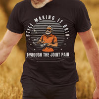Black t-shirt with a gray-bearded man in an orange golf shirt raining dollar bills