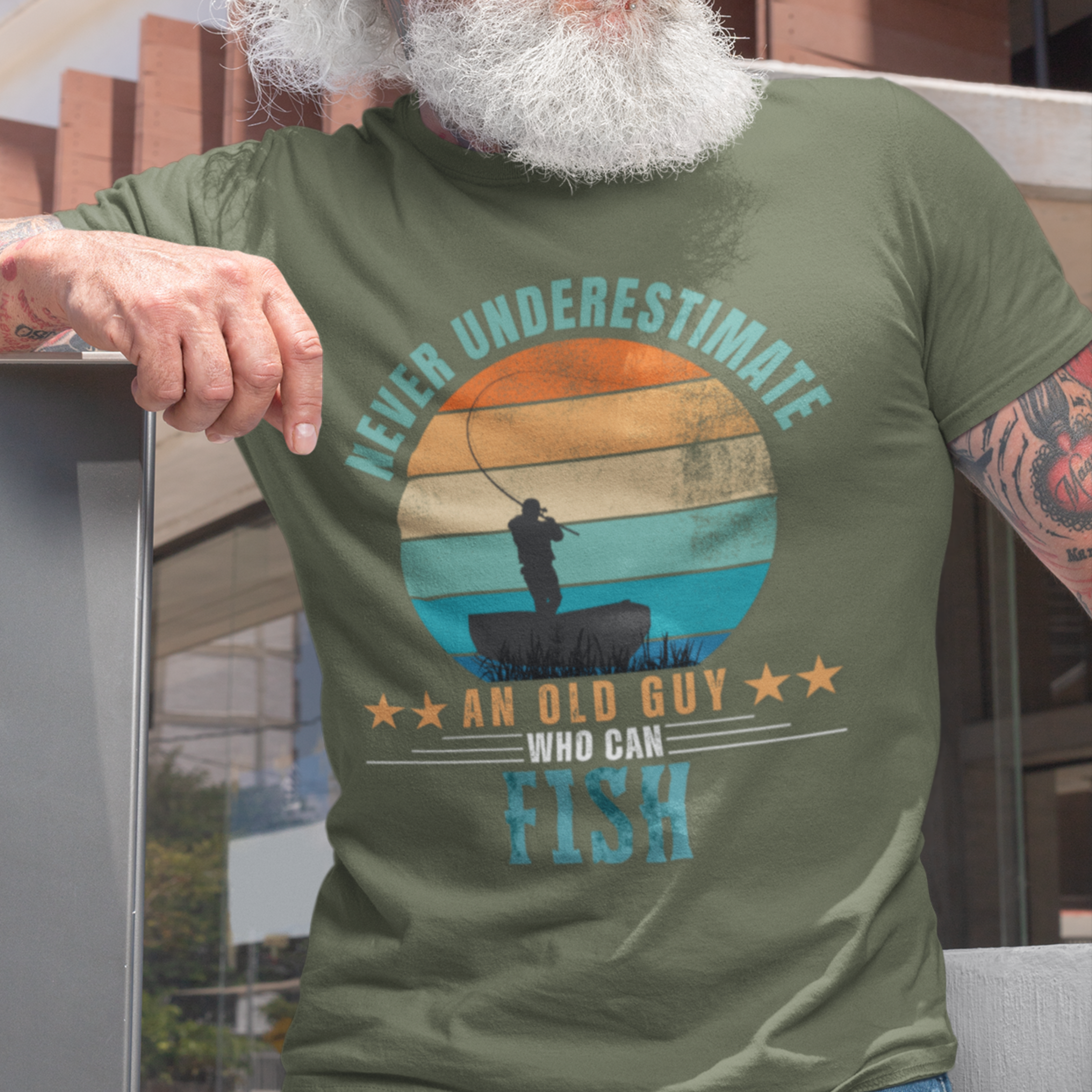 Military green tee featuring silhouette of a fisherman in his boat cast against a stylish distressed striped sunset 