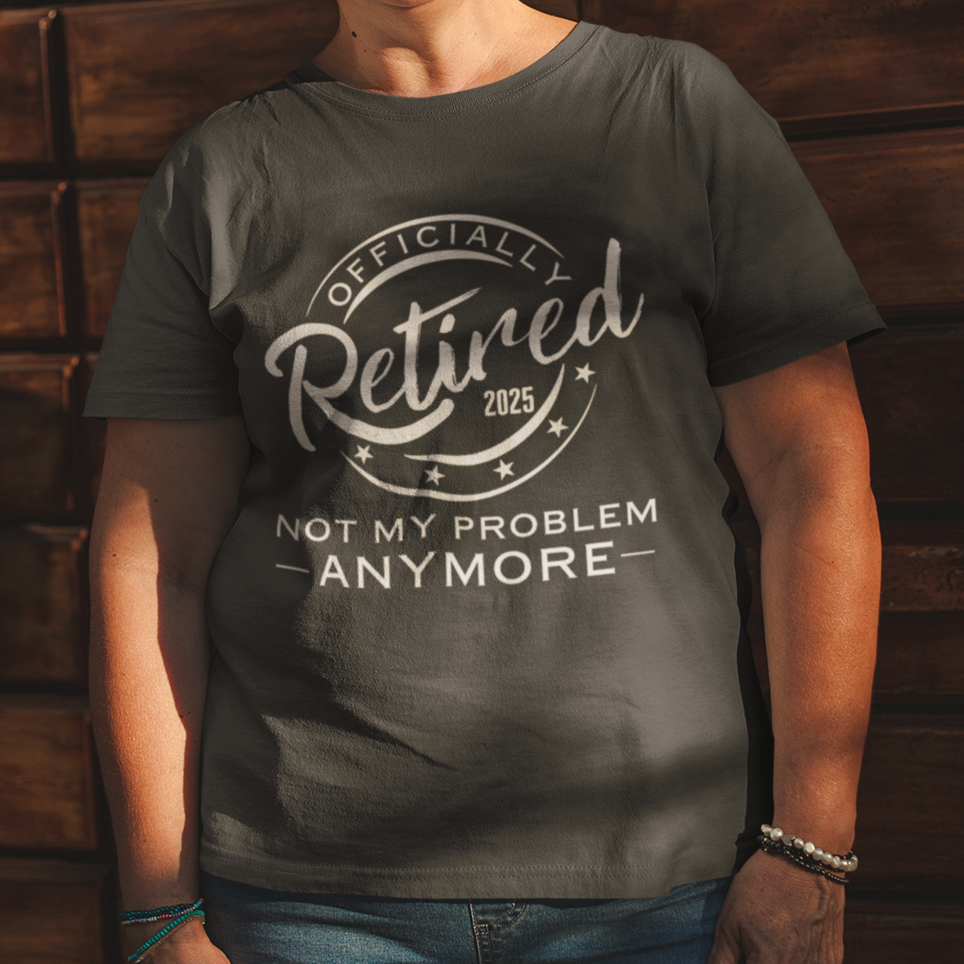 Black tee featuring a replica of an official stamp embossing that reads "Officially Retired 2025 Not My Problem Anymore"