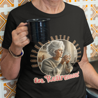 Black tee featuring a senior woman at her kitchen table enjoying a hot cup of coffee.