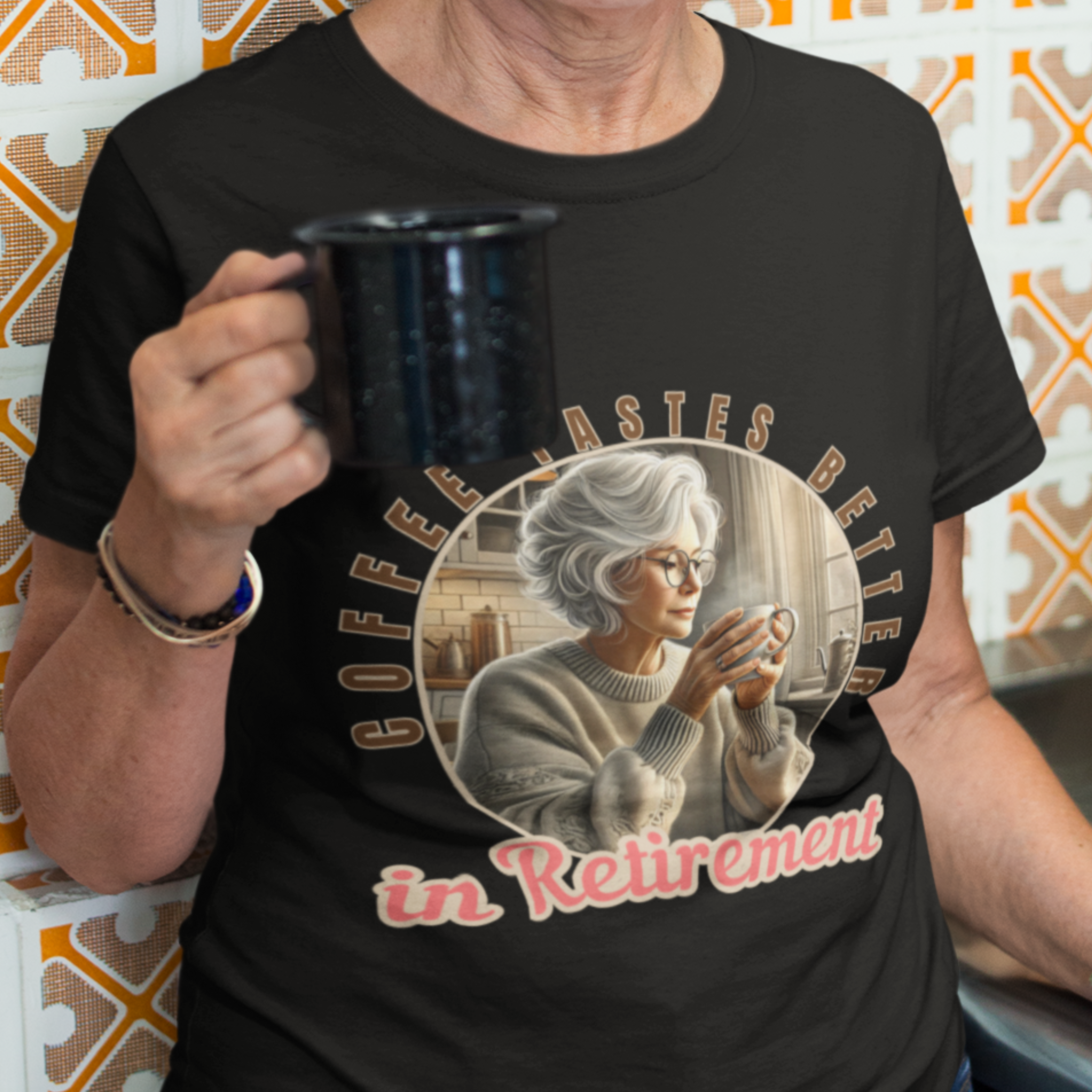 Black tee featuring a senior woman at her kitchen table enjoying a hot cup of coffee.