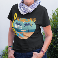 Black tee featuring a hammock between two palm trees on a secluded beach, reading "OLD: Overqualified for Life's Drama"