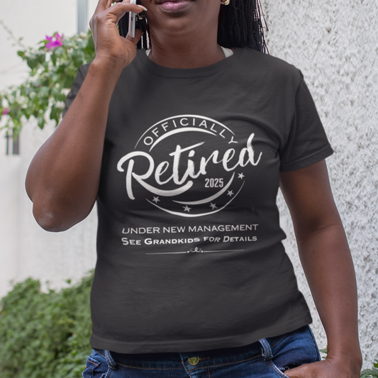 Black tee featuring a replica of an official stamp embossing that reads "Officially Retired 2025 See Grandkids" on a woman. 