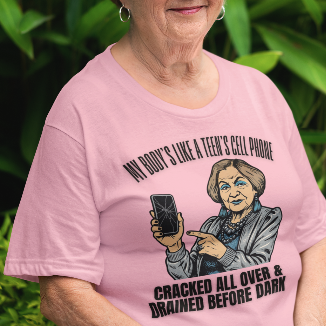 Light pink t-shirt featuring a cartoon older woman pointing to a broken cell phone 